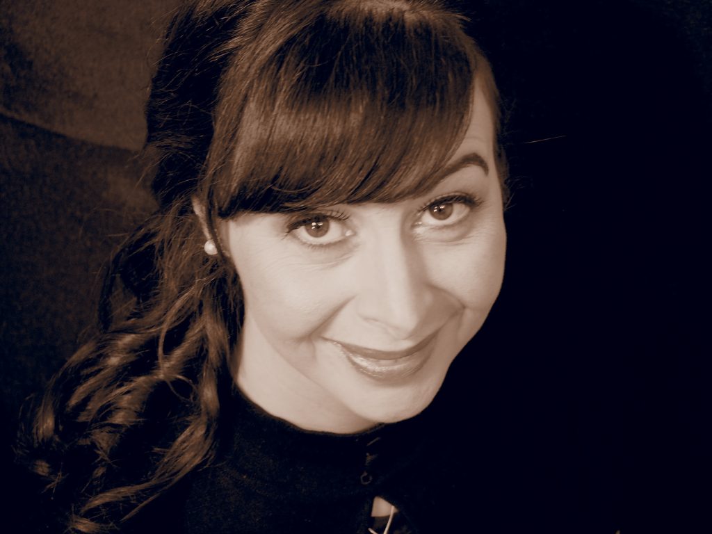 Portrait en noir et blanc d’une illustratrice souriante, photographiée en studio, utilisé pour présenter son travail en création print et digitale.